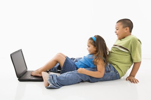 Brother and sister putting feet on laptop computer and smiling.