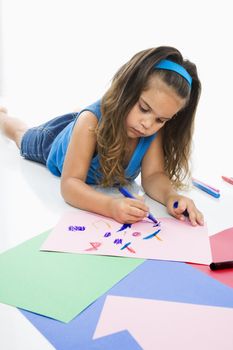 Young latino girl coloring on construction paper.