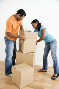 African American male and female couple packing cardboard boxes.