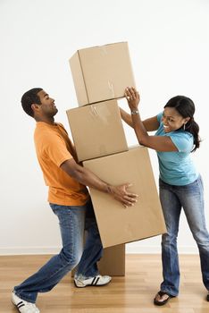 African American female placing boxes on large stack man is holding.