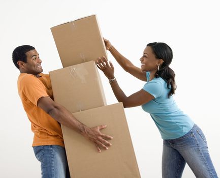 African American woman placing boxes on large stack man is holding.