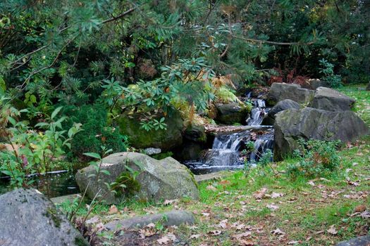 small beautiful falls among stones and autumn leaves