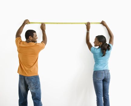African American male and female measuring wall.