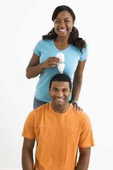 African American female holding energy-saving lightbulb over man's head.