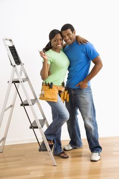 Portrait of smiling African American male and female couple with home repair tools and ladder.