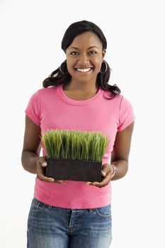 Portrait of smiling African American female standing holding patch of potted grass.