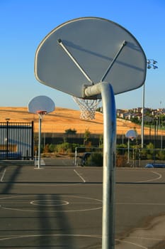 Basketball court on a sunny day in a park.

