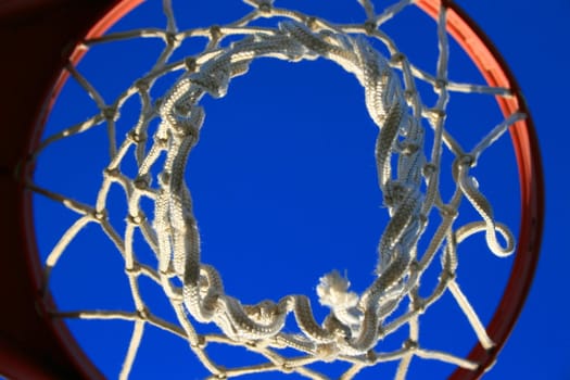 Basketball net over clear blue sky.
