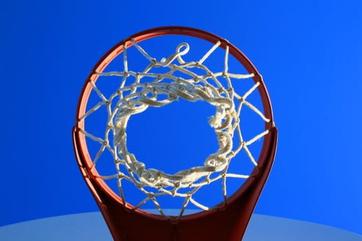 Basketball net and backboard over clear blue sky.
