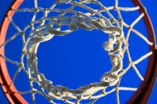 Basketball net over clear blue sky.
