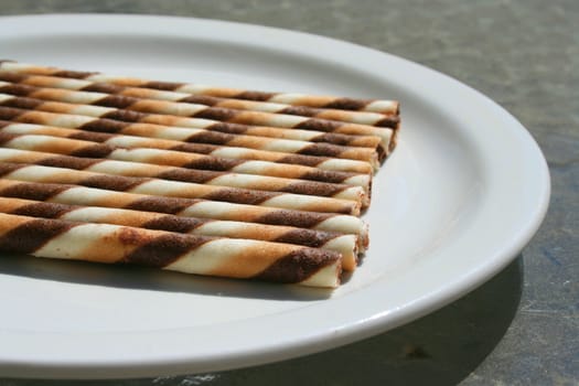 Close up of chocolate cookie sticks on a plate.
