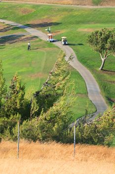 Golfers in golf carts on a big golf course.
