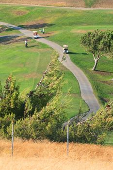 Golfers in golf carts on a big golf course.
