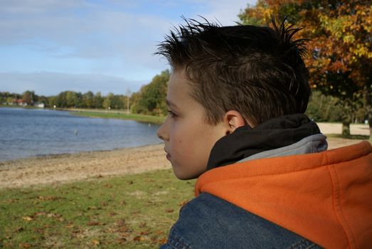 Young boy watching over water.