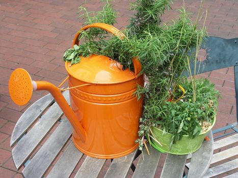 Orange watering can standing on table.