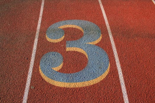 Close up of a number three on a running lane.
