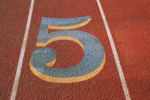 Close up of a number five on a running lane.
