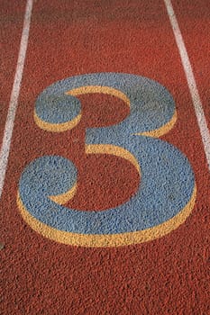 Close up of a number three on a running lane.
