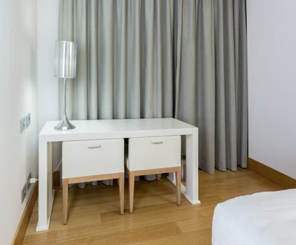 Modern white table desk and two chairs in hotel room at night