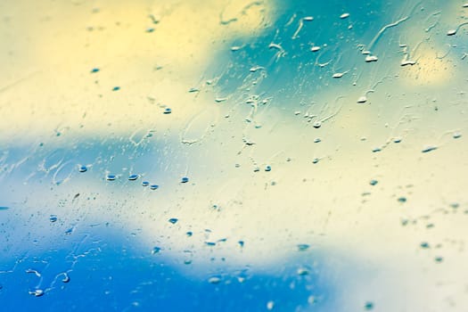 Drops of rain on glass on background of cloudy sky