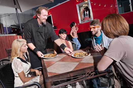 Hipster group served pizza by mobile cafe chef