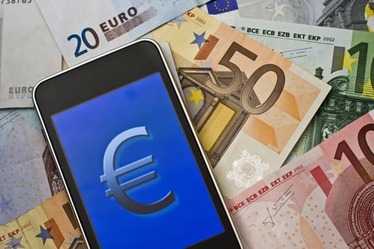 euro symbol on handheld laying on euro banknotes