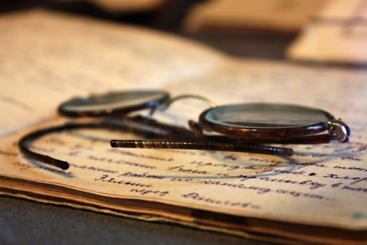 Old glasses lying on the handwritten notebooks.