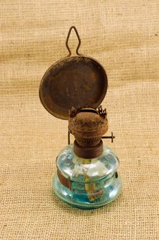 rusty retro kerosene lamp on burlap rural background.