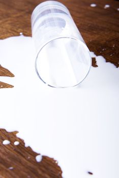 Milk spilled from glass on wooden surface