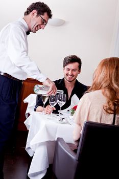 man and woman for dinner in restaurant waiter serving mineral water 