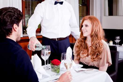 man and woman for dinner in restaurant waiter serving mineral water 