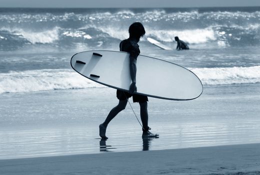 Man-surfer with board on a coastline. Bali. Indonesia