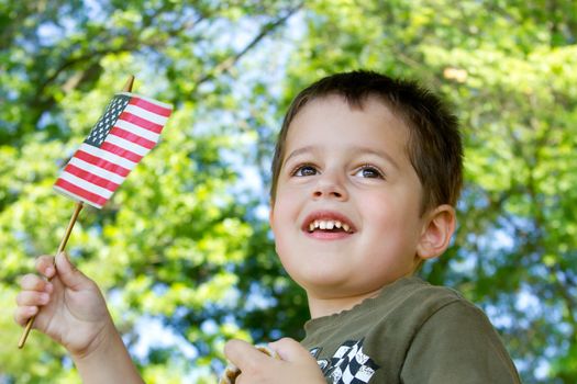 Portrait of a cute brown-haired, brown-eyed boy waving an American flag as he watches a parade