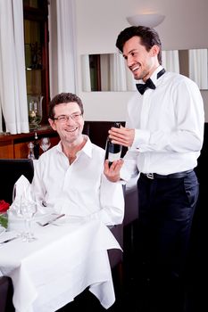 man and woman in restaurant for dinner drinking red wine and smiling