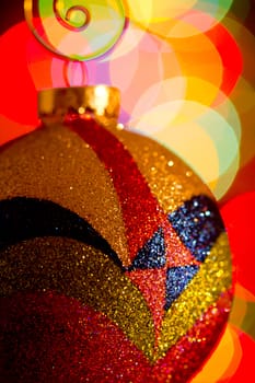 Glittery multi-colored Christmas ornament with out-of-focus lights in the background