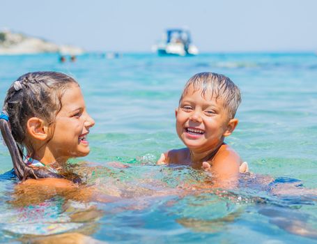 Happy kids. Sister and brother playing and swimming in the transparent sea