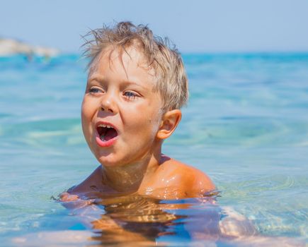 Portrait of young boy swimming in the transparent sea