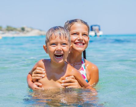 Happy kids. Sister and brother playing and swimming in the transparent sea