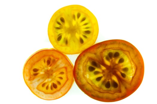 Slices of red, yellow, and orange grape tomatoes on a white background