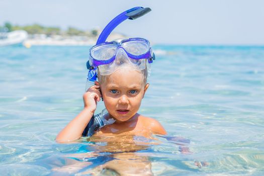 Portrait of young boy in snorkling equipment swimming in the transparent sea