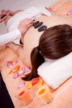 young attractive woman get hot stone massage by professional in wellness spa salon