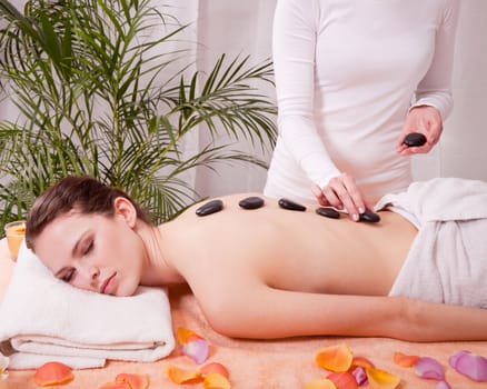 young attractive woman get hot stone massage by professional in wellness spa salon