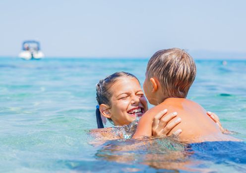 Happy kids. Sister and brother playing and swimming in the transparent sea