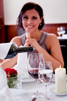 man and woman in restaurant for dinner drinking red wine and smiling