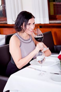 man and woman in restaurant for dinner drinking red wine and smiling