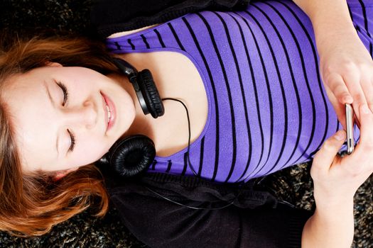 young smiling teenager girl at home with mp3 player and earphones listening to music