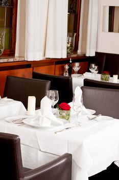 tables in restaurant with white tablecloth and elegant dish and silverwear