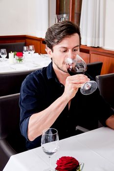 man and woman in restaurant for dinner drinking red wine and smiling