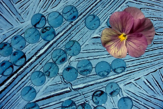 A blue abstract with a pink flower in the upper right corner