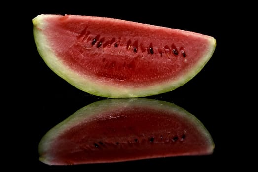 A slice of watermelon on a reflective background